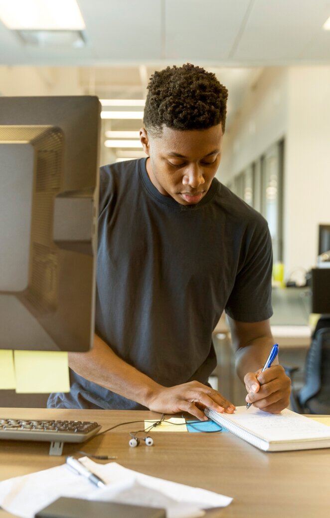 Man at desk writing in notebook