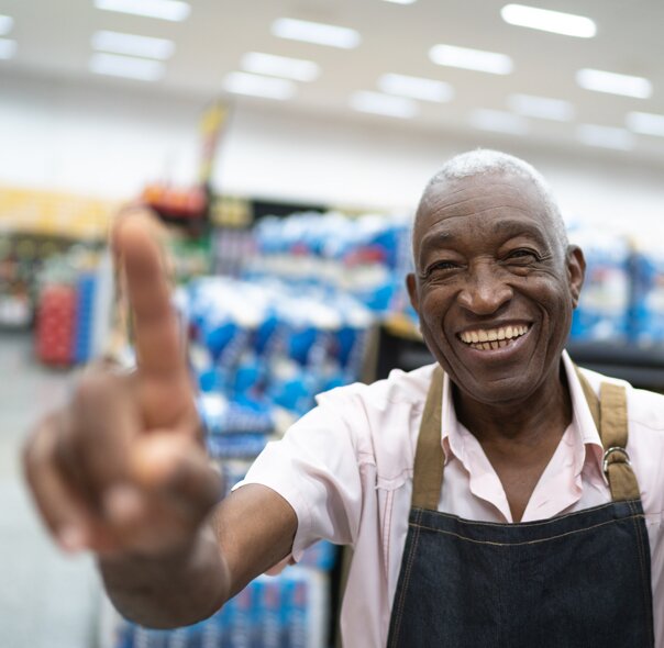 Grocery store employee holding up hand pointing up
